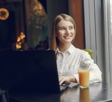 Girl in a cafe. Woman in a white blouse. Lady use a laptop.