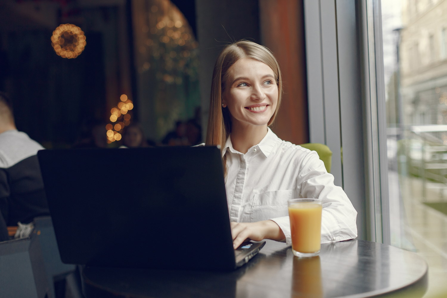 Girl in a cafe. Woman in a white blouse. Lady use a laptop.