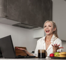 girl-working-on-laptop-in-kitchen-at-home-and-very-emotional-woman-gestures-with-hands